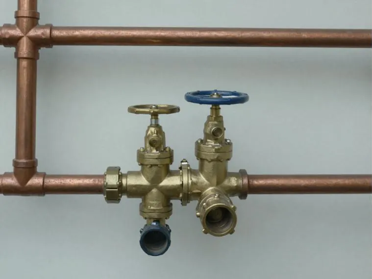 Brass shutoff valves and test fittings mounted on copper supply pipework.